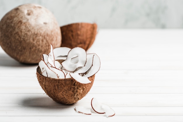 Coconut chips in a brown bowl on a white wooden 