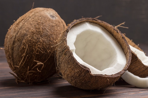 Coconut, chopped in half coconut on dark wooden background.