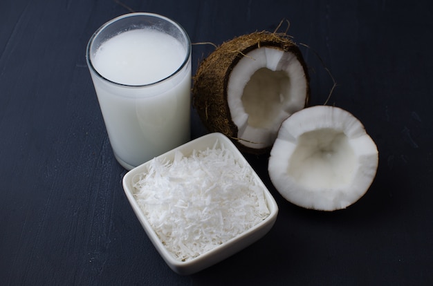 Coconut, coconut shavings and coconut milk on a black background.