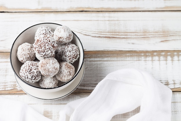 Coconut energy balls in a white cup. Copy space. Healthy food