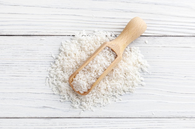 Photo coconut flakes und scoop on white wooden background