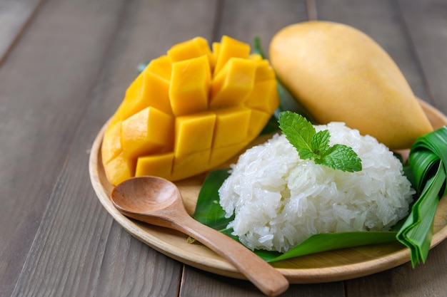 Coconut Flavored Sticky Rice with Ripe Mango on wood dish xAPopular Thai desserts on summer