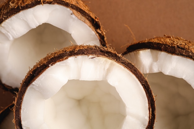 Foto la noce di cocco fruttifica su fondo normale marrone, il concetto tropicale dell'alimento astratto, macro di vista superiore