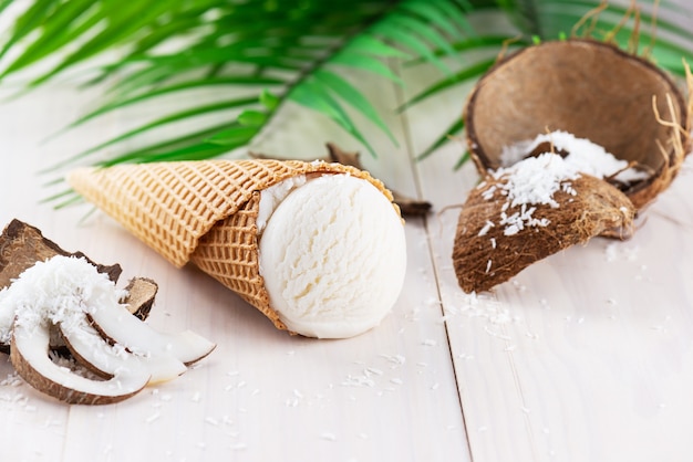 Gelato al cocco con un ramo di palma su un tavolo di legno bianco