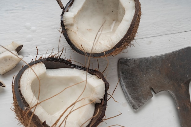 A coconut is chopped in half on a light wooden table. Top view