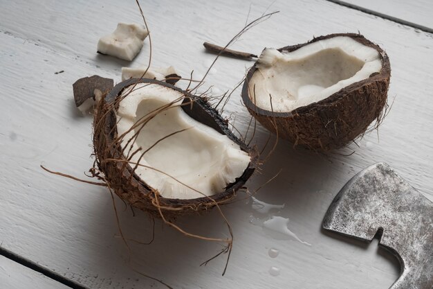 A coconut is chopped in half on a light wooden table Top view