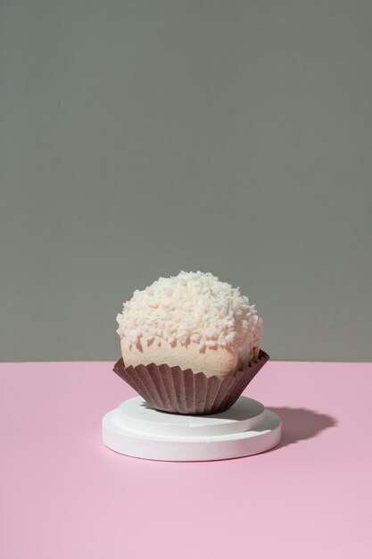 Coconut macaroon on a podium on pastel pinkgreen background