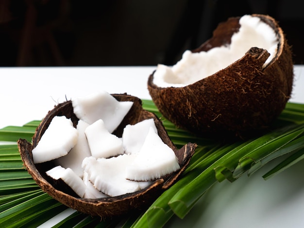 Coconut meat and coconut leaf on white table