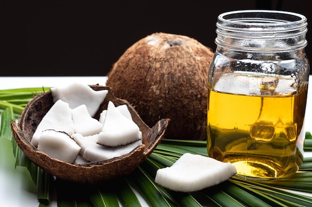 Photo coconut meat and coconut oil in glass bottle on coconut leaf