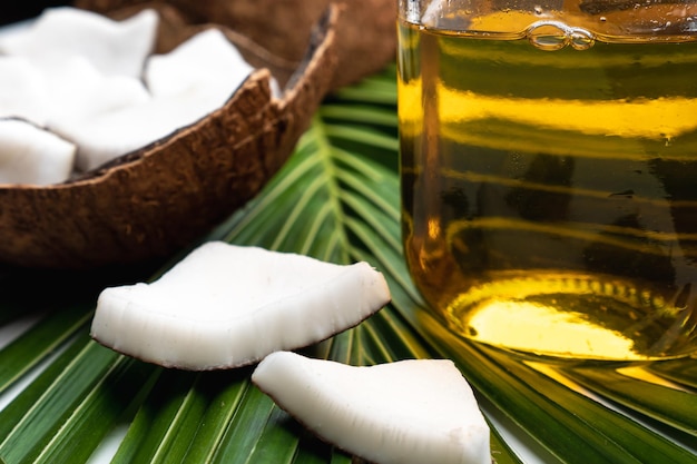 Coconut meat and coconut oil in glass bottle on coconut leaf