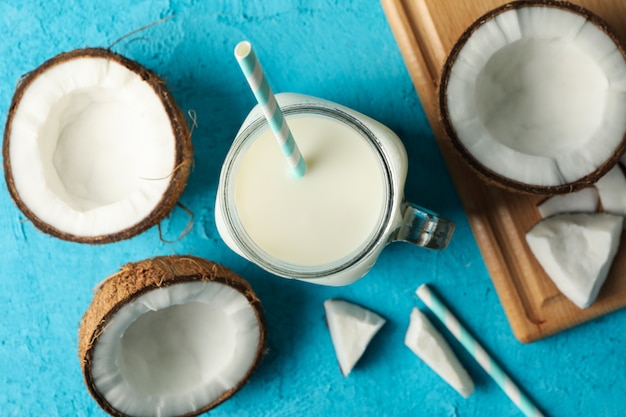 Photo coconut and milk on blue, top view