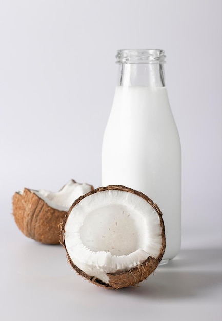 Coconut milk in a bottle and fresh coconut on a white background Vegetarian food Vertical format