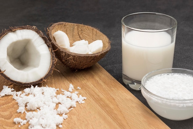 Foto latte di cocco in bicchiere e ciotola fiocchi di cocco cocco semi freschi gusci di cocco a bordo