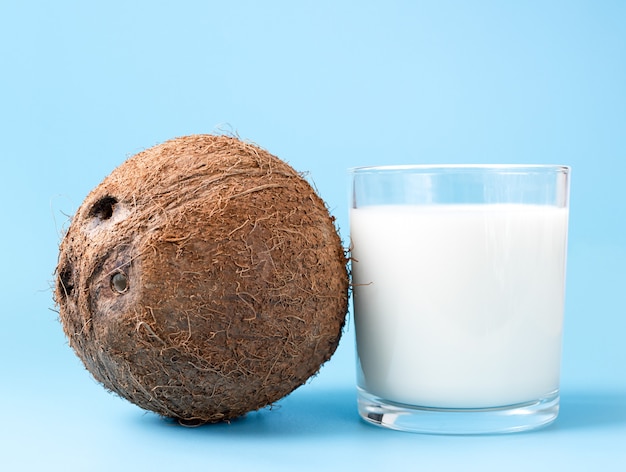 Coconut Milk in a glass and coconut on blue background with copy space.