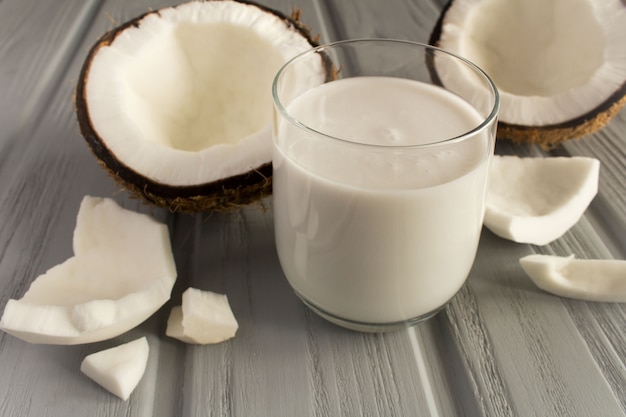 Coconut milk in the glass on the grey wooden background