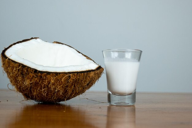 ココナッツミルクを木製のテーブルに載せ、乾燥した茶色のココナッツを半分に割ったもの