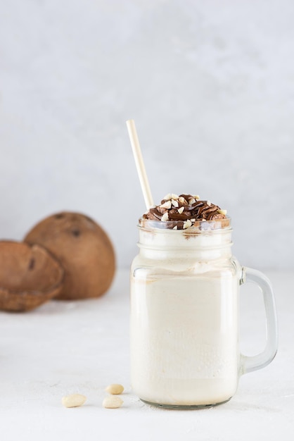 Coconut milkshake with chocolate and nuts on a light table Vegan sugar and lactose free