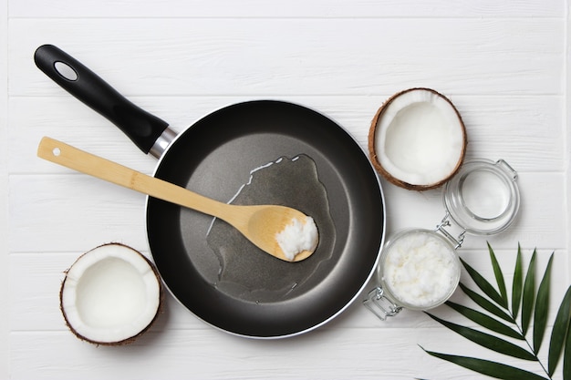 Coconut oil and a frying pan on a wooden table closeup