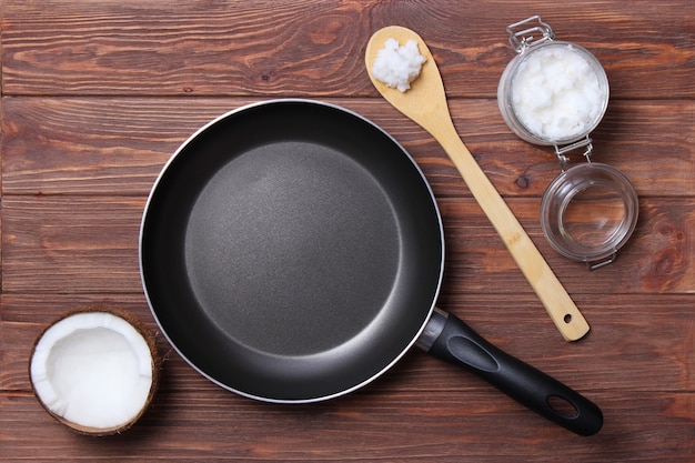 Coconut oil and a frying pan on a wooden table closeup