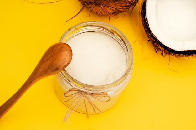 Photo coconut oil jar near parts of coconut on a colored background