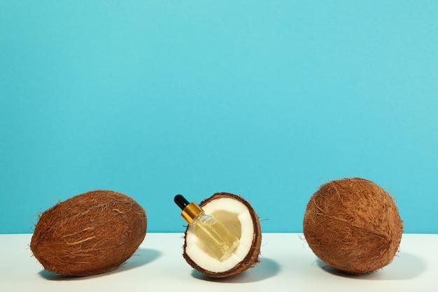 Coconut oil with coconut on blue background. Vertical photo.