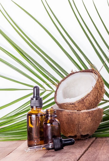 Coconut oil with coconut on a palm leaf wall on a wooden table.