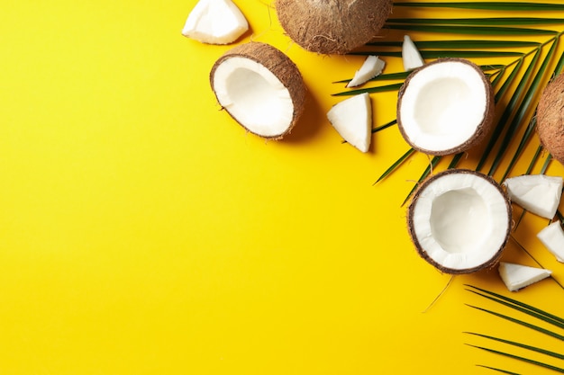 Coconut and palm branch on yellow table. Tropical fruit