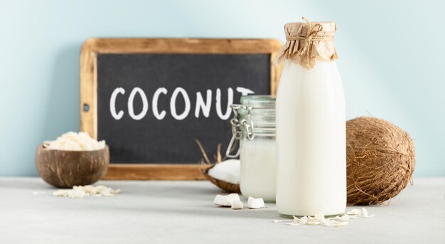 Coconut products fresh coconut oil milk and chalkboard with Coconut lettering on blue background