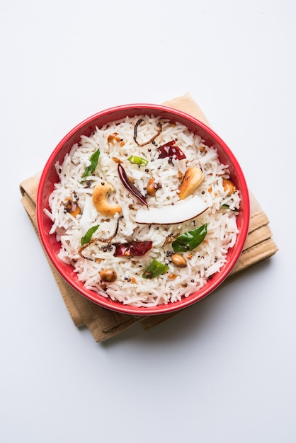 Кокосовый рис - южно-индийский рецепт с использованием остатков вареного риса басмати, подается в красной миске на мрачном фоне, выборочный фокус