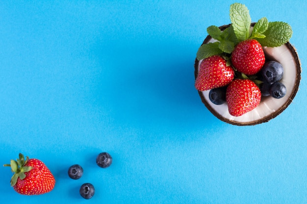 Coconut,strawberry and blueberries on the blue table.Top view.