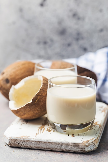 Latte vegano di cocco non latticini in un bicchiere sulla superficie grigia con spazio di copia