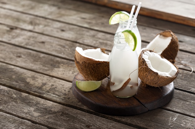 Coconut water in bottles on wooden table. Healthy veggie drink