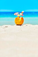 Кокос с разноцветными зонтиками и соломкой на пляже