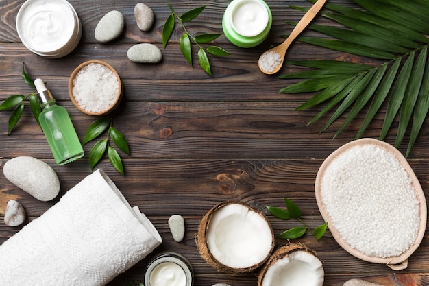 Coconut with jars of coconut oil and cosmetic cream on colored background Top view Free space for your text Natural spa coconut cosmetics and organic treatment concept Coconut Spa composition