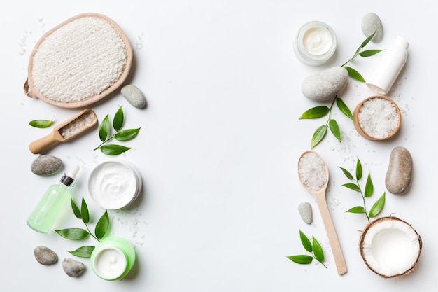 Coconut with jars of coconut oil and cosmetic cream on colored background Top view Free space for your text Natural spa coconut cosmetics and organic treatment concept Coconut Spa composition