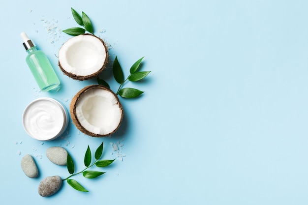 Coconut with jars of coconut oil and cosmetic cream on colored background Top view Free space for your text Natural spa coconut cosmetics and organic treatment concept Coconut Spa composition