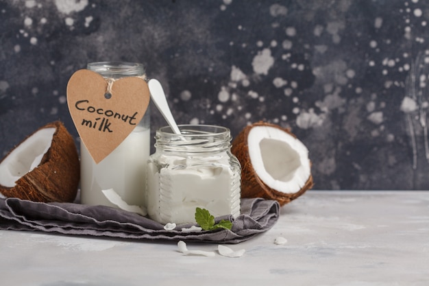 Noce di cocco e latte di cocco in un barattolo di vetro. concetto sano dell'alimento del vegano, fondo scuro, spazio della copia