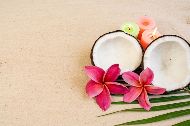 Coconuts and candles on a table with a pink flower in the middle