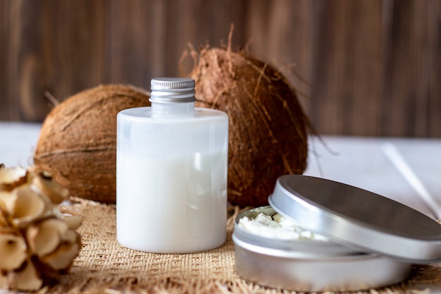 Coconuts and coconut oil in a metal pot. Wooden background.