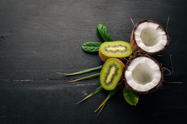 Coconuts and kiwi on a wooden background Tropical fruits and nuts Top view Free space for text