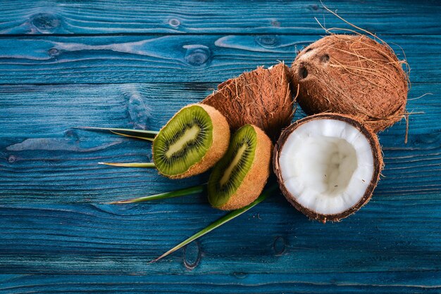 Coconuts and kiwi on a wooden background Tropical fruits and nuts Top view Free space for text