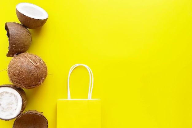 Coconuts and paper shopping bag on a bright yellow background Copy Space