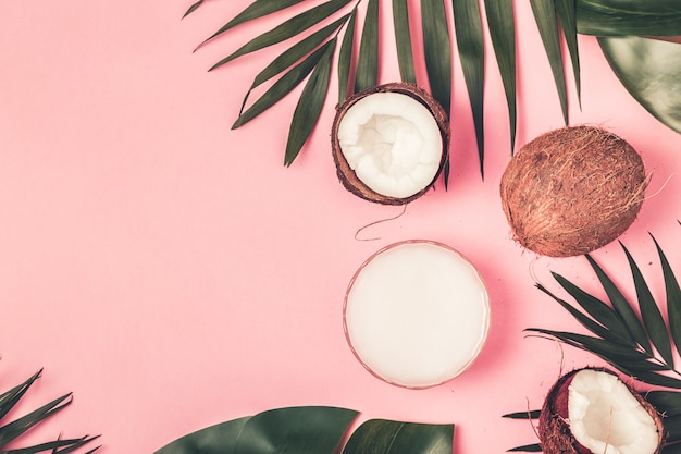 Coconuts on a pastel background with tropical leaves