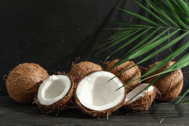Coconuts with palm branch on wooden table against black