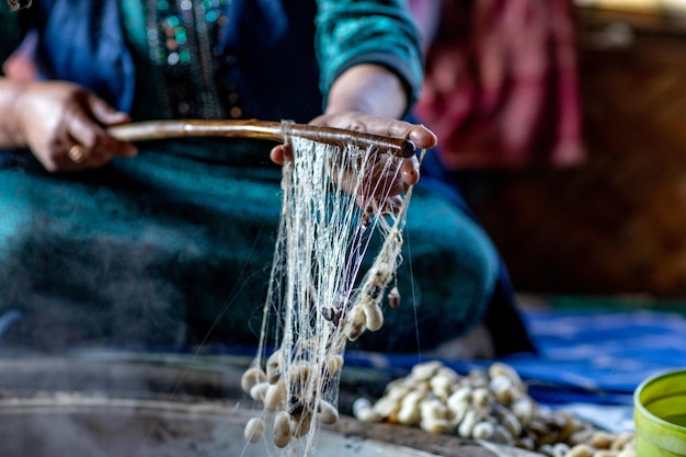 The cocoons are boiled in the cauldron to spin the fiber into the spool