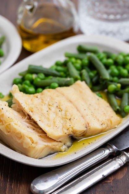 Cod fish with green beans and peas on dish