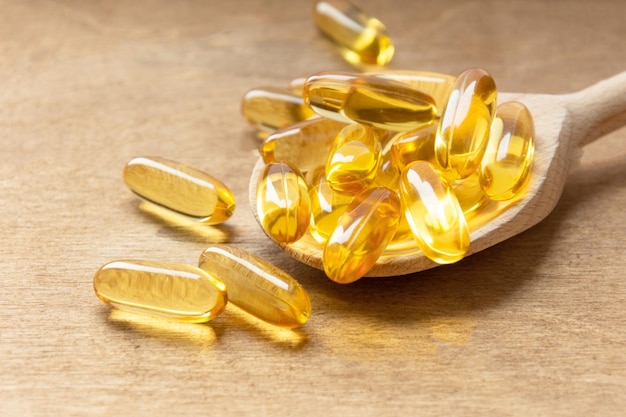 Cod liver oil omega 3 gel capsules on a spoon on wooden background