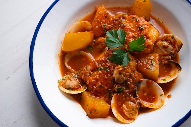 Cod loins cooked in the oven with tomato and clams.