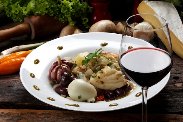 Foto baccalà con verdure e bicchiere di vino rosso