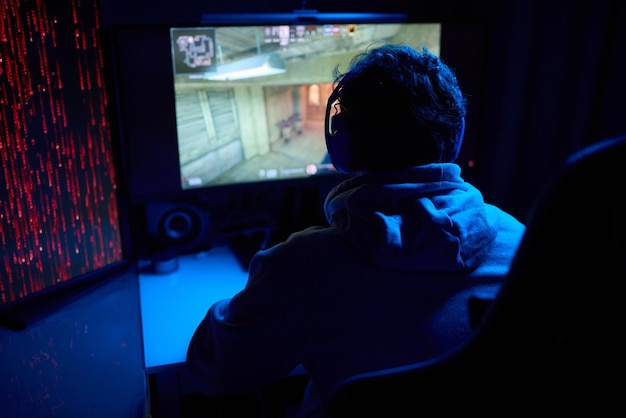 a coder is working late at night on a computer screen coding and using a smartphone app